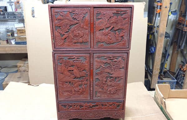 Cinnabar “Kang” Qing Dynasty Cabinet For Sale.This 18th century miniature finely carved Chinese cabinet has small drawers and compartments. The color is vivid and the details are beautiful. It's a landscape picture of scholars outside.